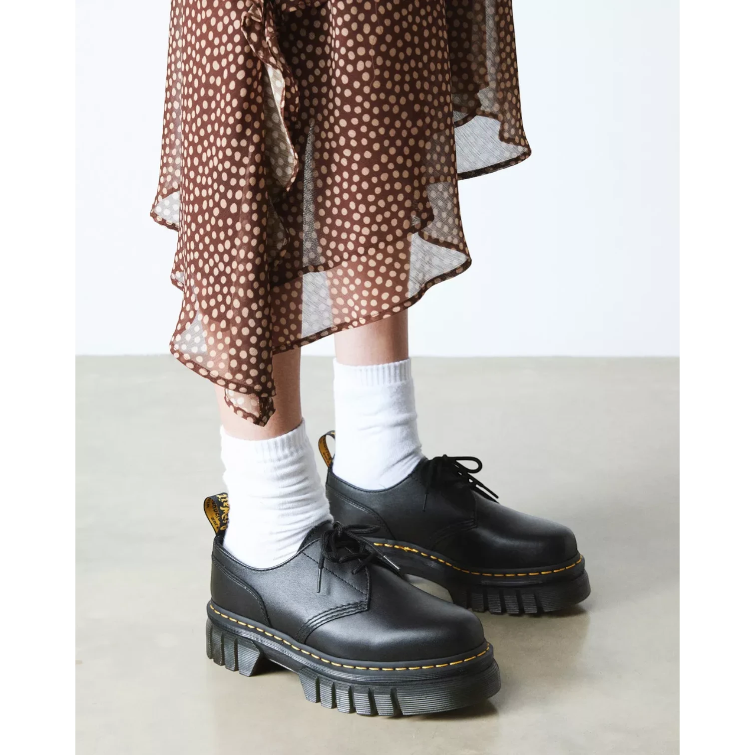 My Store Dr. Martens Audrick Nappa Lux black leather platform shoes with white socks and a brown polka dot dress.