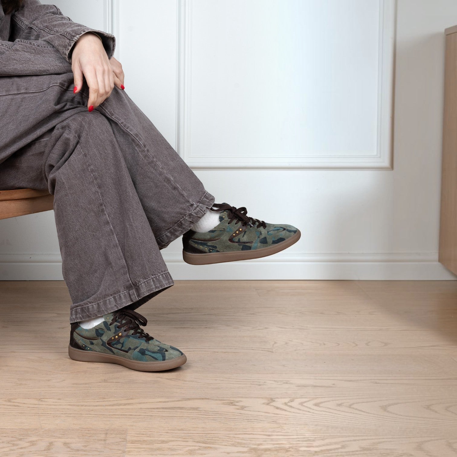 ShoeShop 13POE sneakers featuring a green camouflage pattern, brown laces, and a flat rubber sole worn with grey jeans