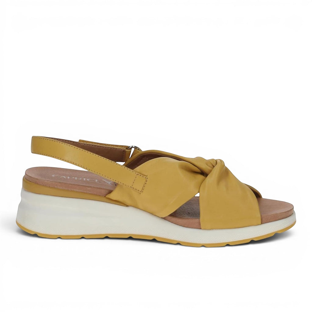 ShoeShop Caprice mustard yellow leather wedge sandals with a knotted front strap and adjustable slingback closure.