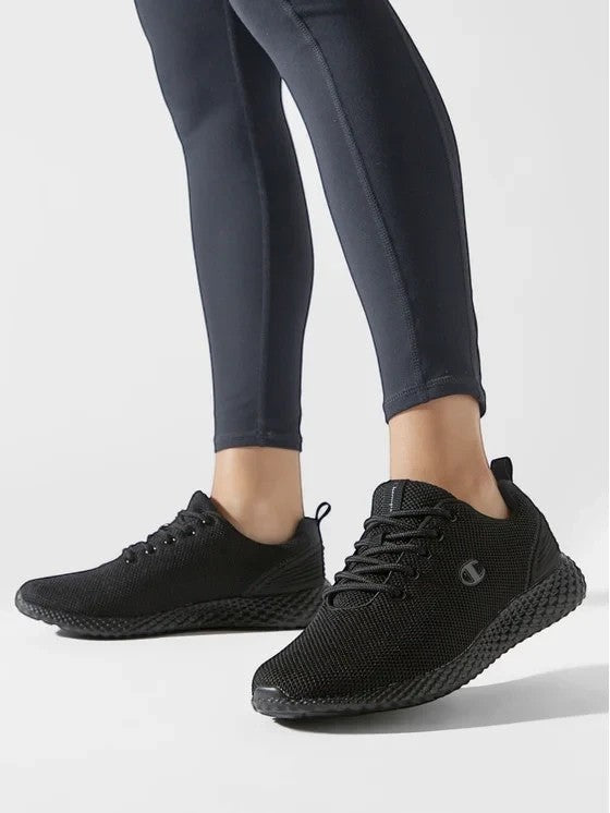 ShoeShop Champion S11496 black mesh sneakers with textured soles worn by a person in black leggings.