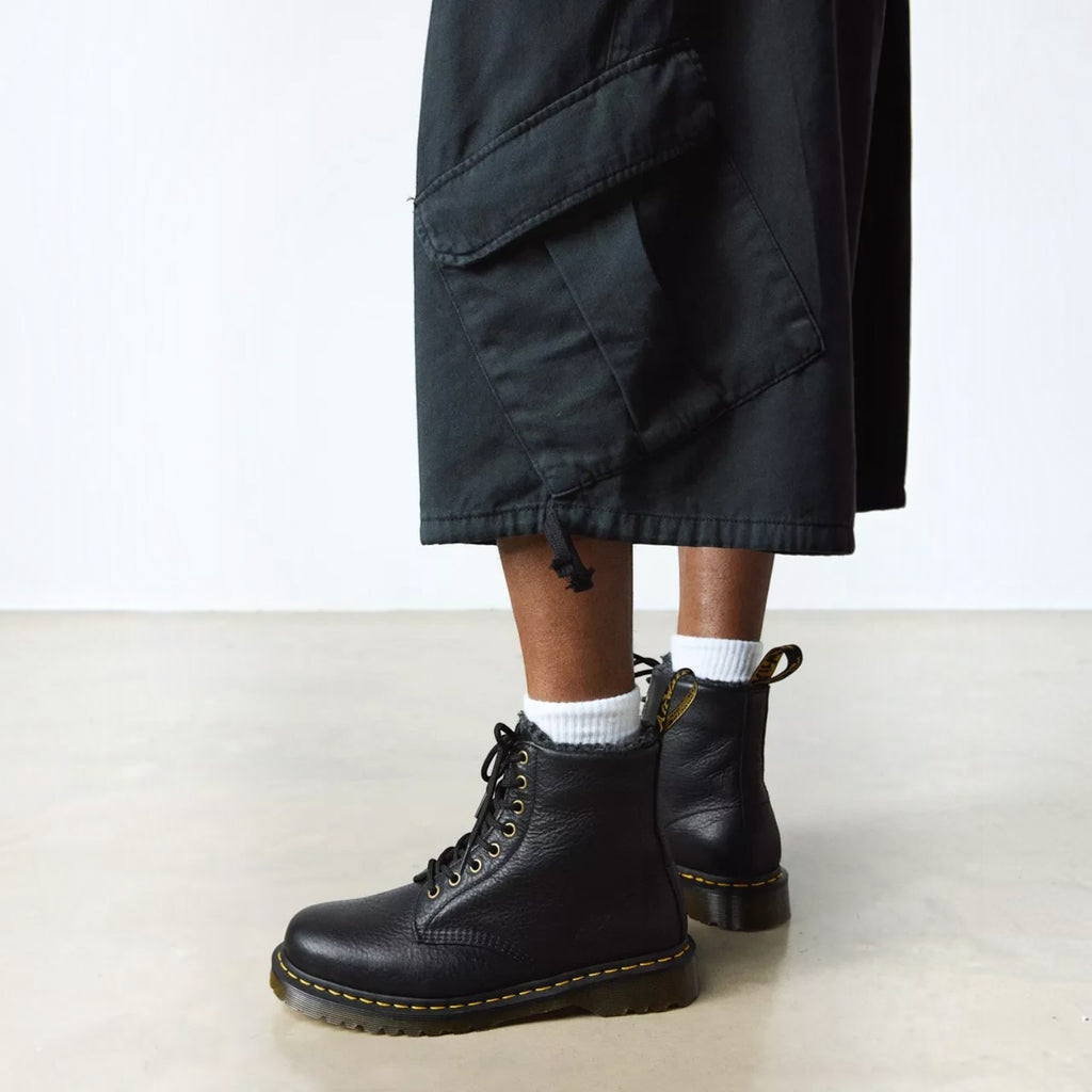 ShoeShop Dr. Martens 1460 black grizzly leather boots with faux fur lining, yellow stitching, and lace-up closure.