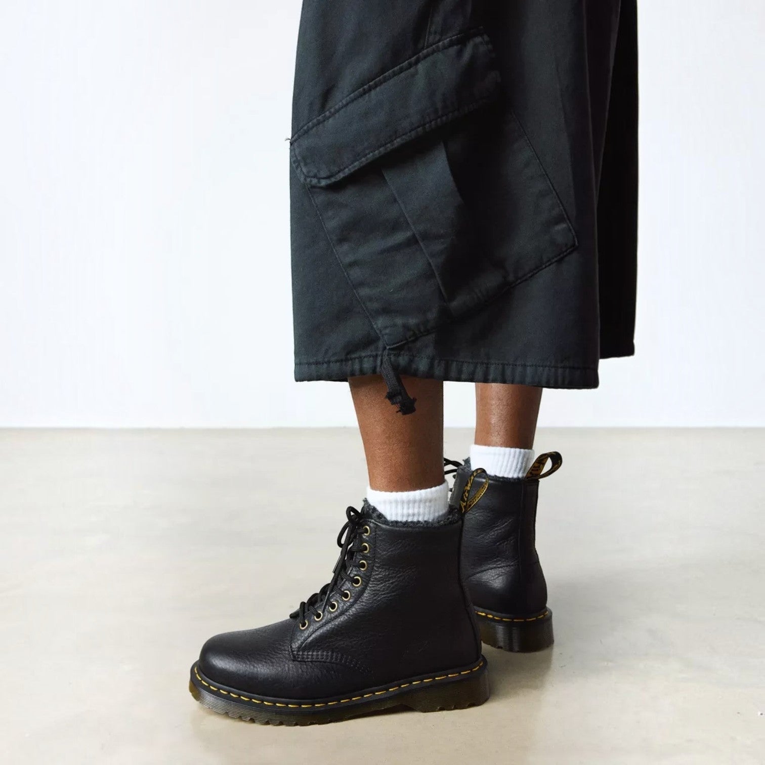 ShoeShop Dr. Martens 1460 black grizzly leather boots with faux fur lining, yellow stitching, and lace-up closure.