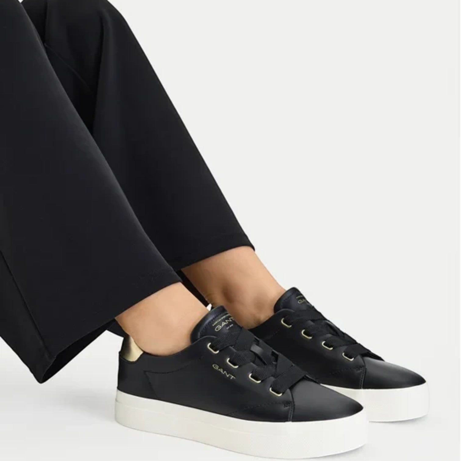 ShoeShop GANT black leather sneakers with gold accents and a thick white platform sole worn by a model.