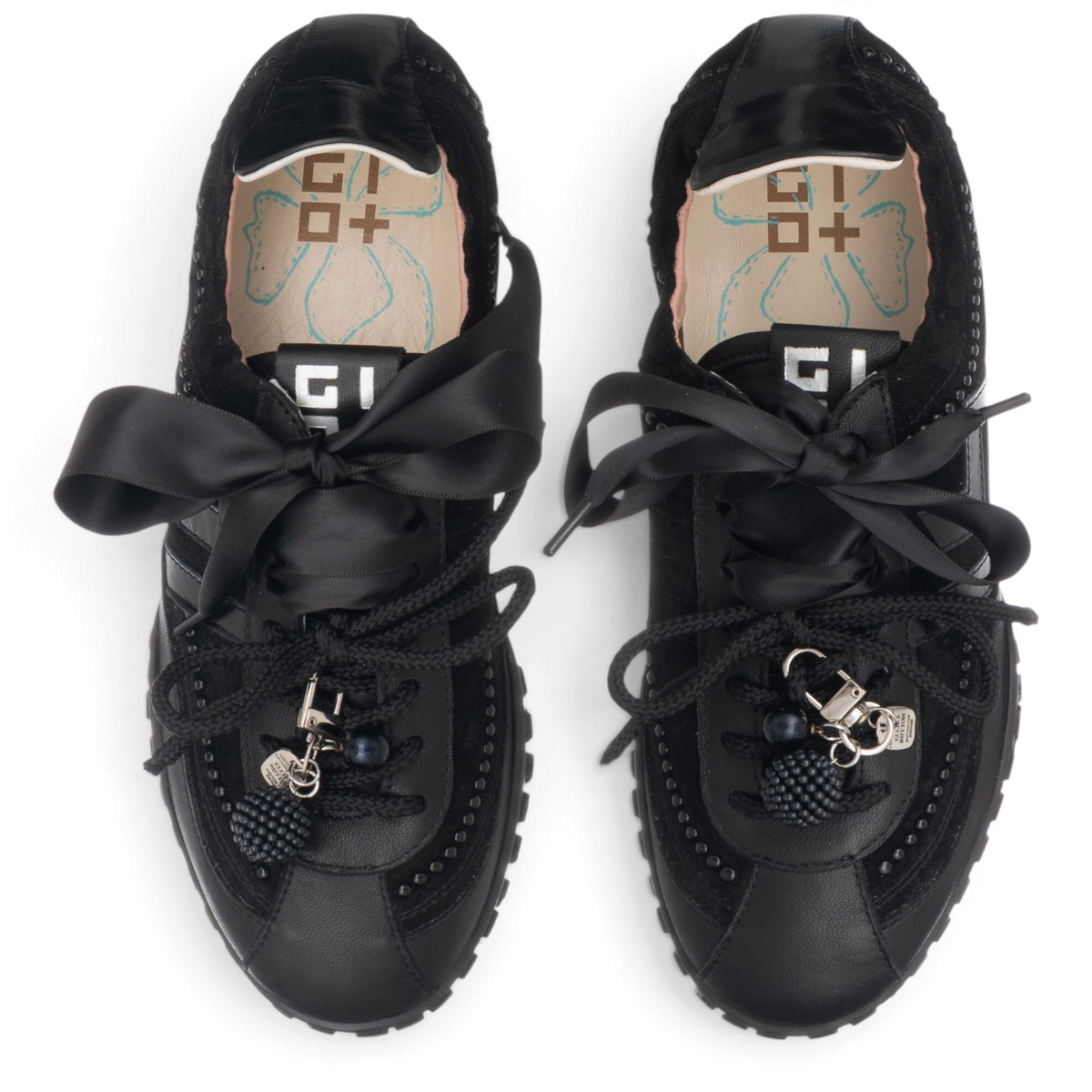 ShoeShop Gio+ CIELOX18 black leather sneakers with satin ribbon laces and decorative charms, top-down view.