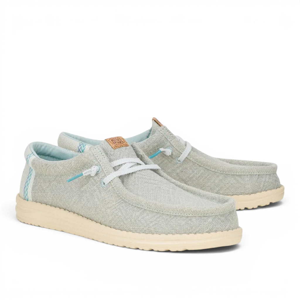 ShoeShop Hey Dude light grey canvas slip-on shoes with white laces and a cream-colored textured rubber sole.