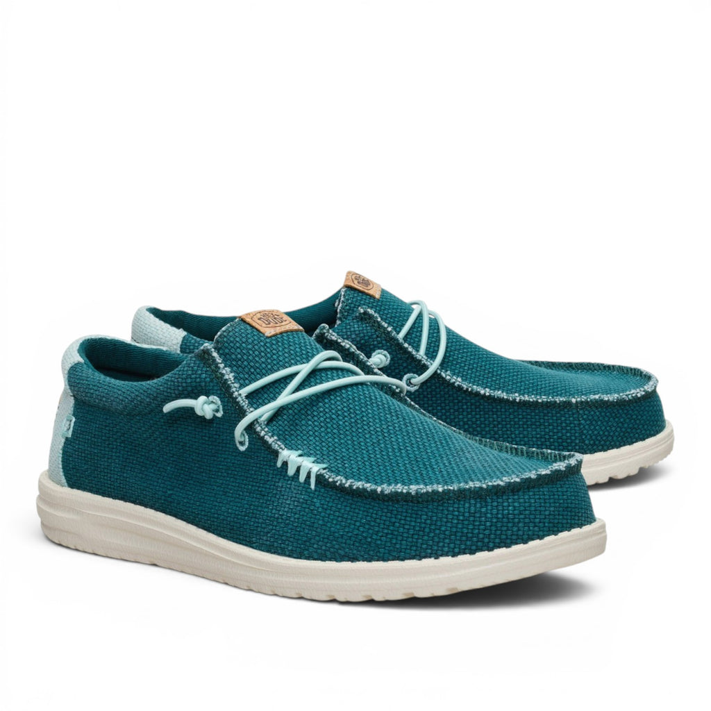 ShoeShop Hey Dude teal canvas slip-on shoes with white textured soles and decorative lace-up detail