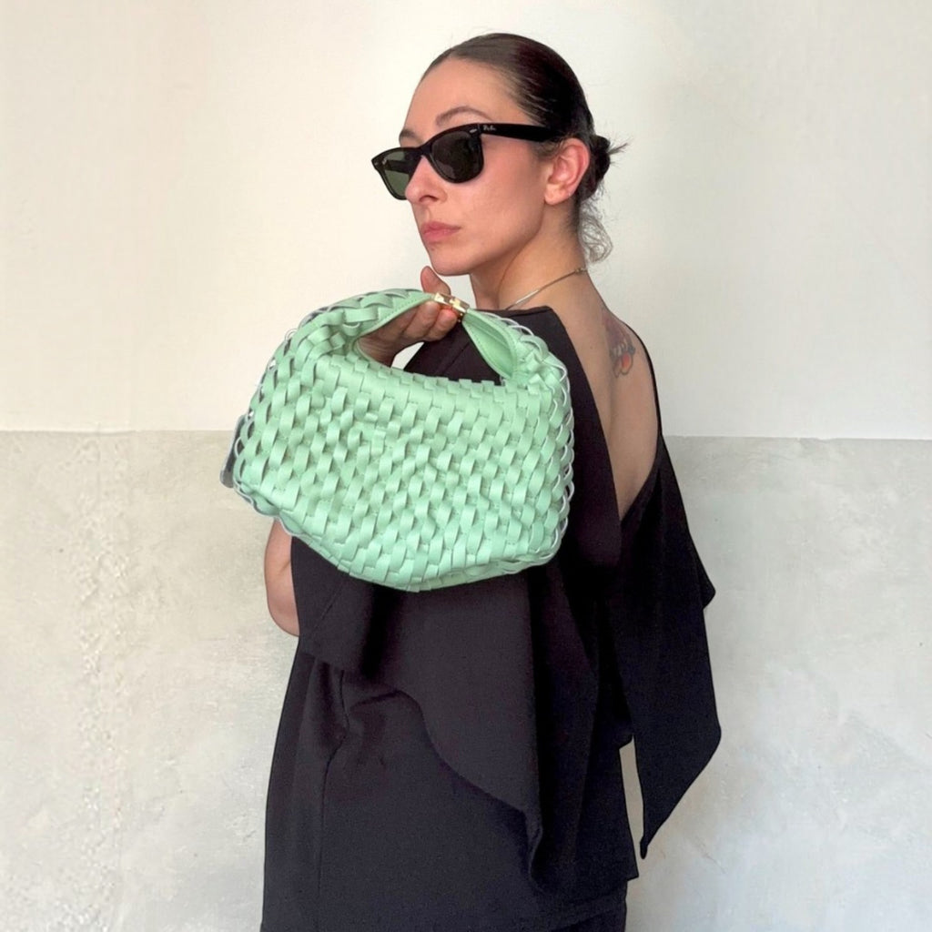 ShoeShop mint green woven handbag held by a woman wearing a black top and sunglasses