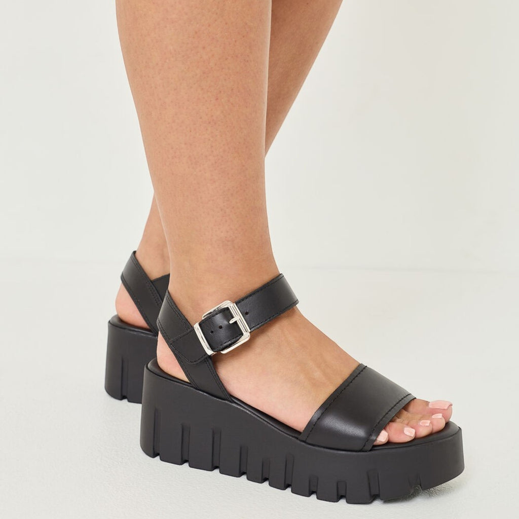 ShoeShop Tamaris black platform sandals with ankle strap and chunky lug sole worn on feet