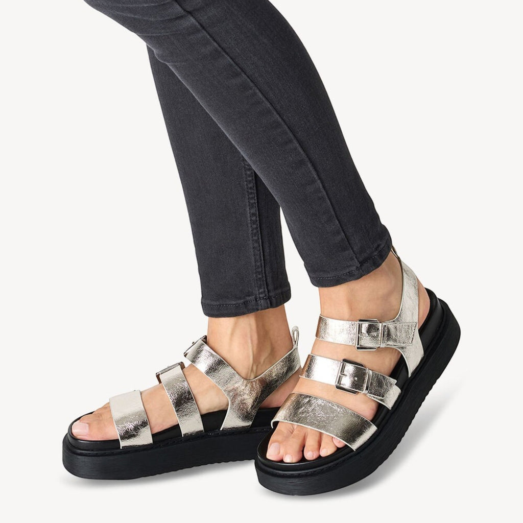 ShoeShop Tamaris metallic silver strappy sandals with buckle closures and a thick black platform sole on a model