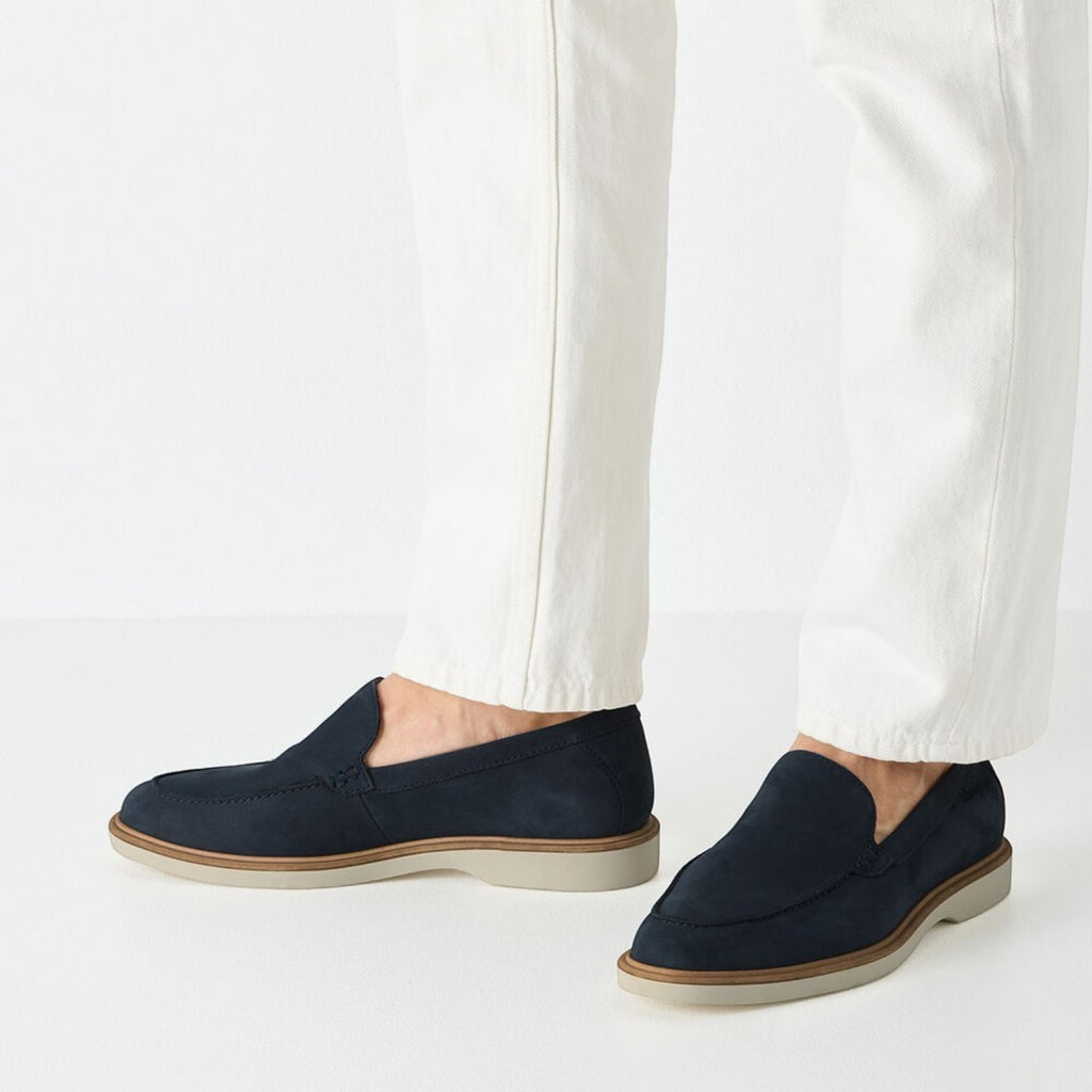 ShoeShop Tamaris navy blue suede loafers with a light grey sole worn with white trousers