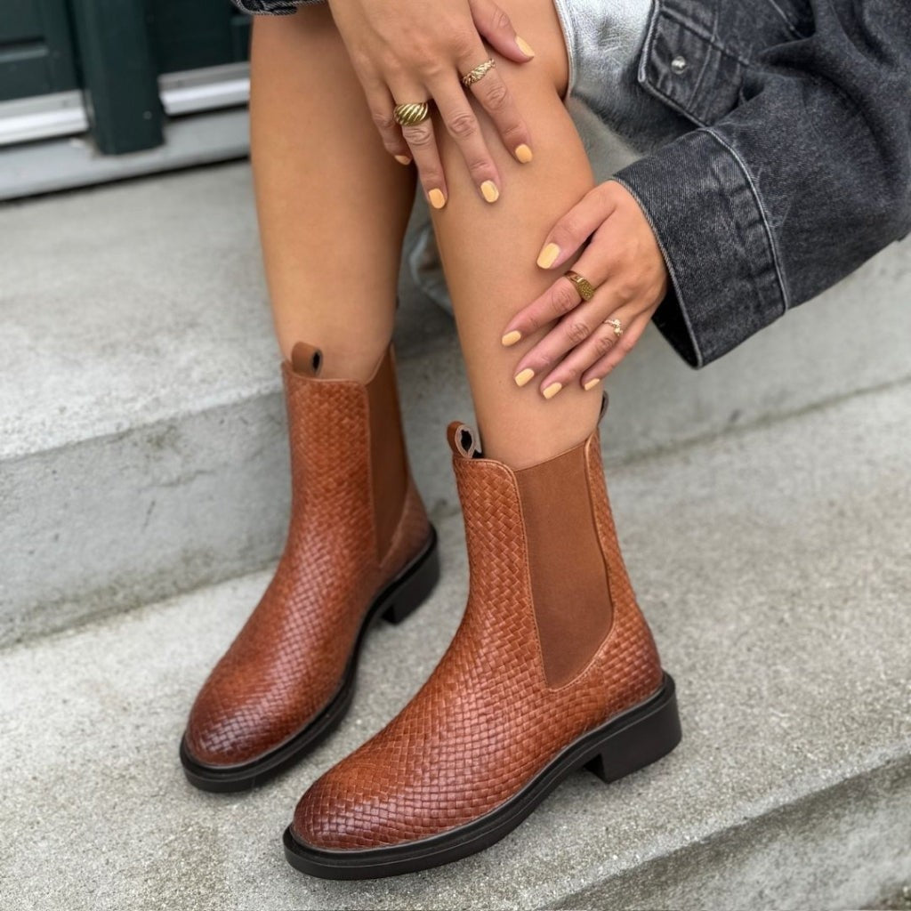 ShoeShop tan woven leather Chelsea boots with elastic side panels and a black rubber sole worn on concrete steps